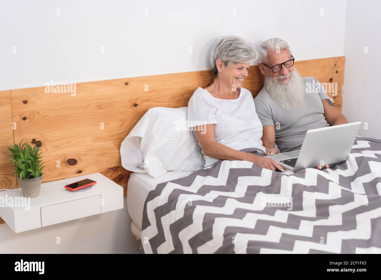 Felice coppia sposata anziana che si trova a letto guardando i video su  Laptop - persone mature che si divertono a casa - tecnologia amore anziano  e concetto di felicità Foto stock - Alamy