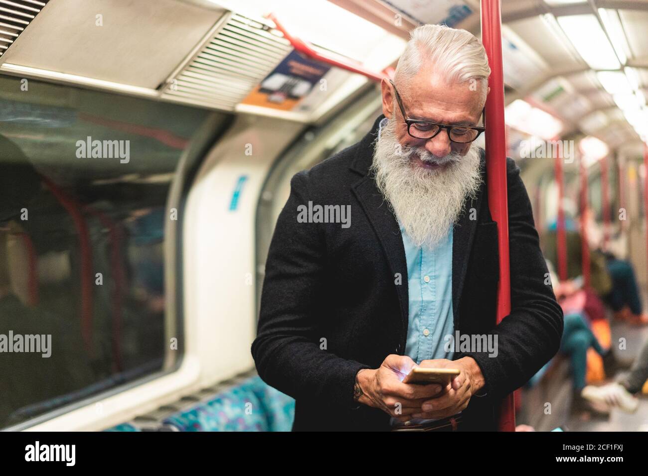 Uomo hipster anziano che usa lo smartphone nella metropolitana sotterranea - Moda la persona matura viaggia in treno e si diverte con la tecnologia Tendenze - sambuco gioioso Foto Stock