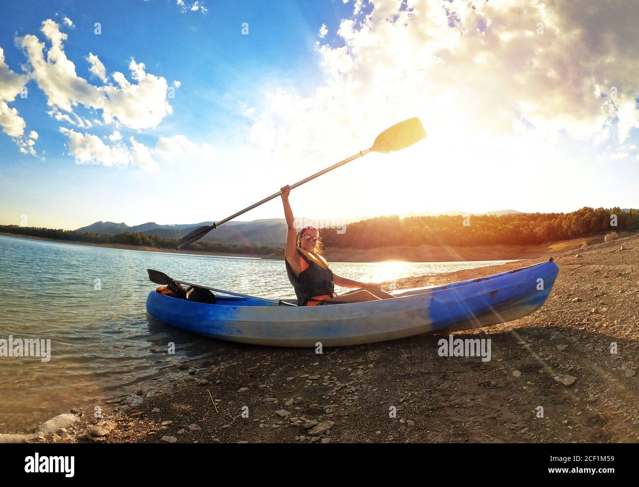 Donna in kayak canottaggio al mare contro il tramonto a Embalse de la Bolera, Jaen, Spagna. Il successo sul concetto di obiettivi sportivi. Potere della donna. Foto Stock