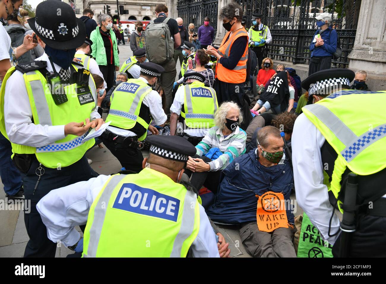 Gli agenti di polizia parlano ai manifestanti della ribellione estinzione organizzando una protesta siedita all'ingresso Carriage Gates alle Houses of Parliament, Londra. Il gruppo della campagna ambientale ha pianificato eventi che si terranno in diversi punti di riferimento della capitale. Foto Stock