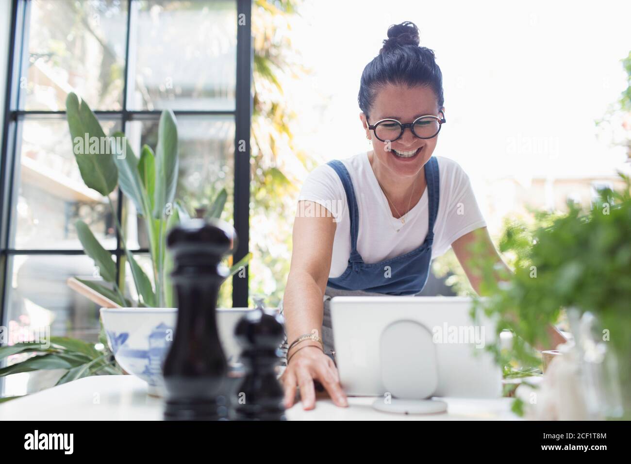 Donna sorridente che usa il tablet digitale al tavolo da pranzo Foto Stock