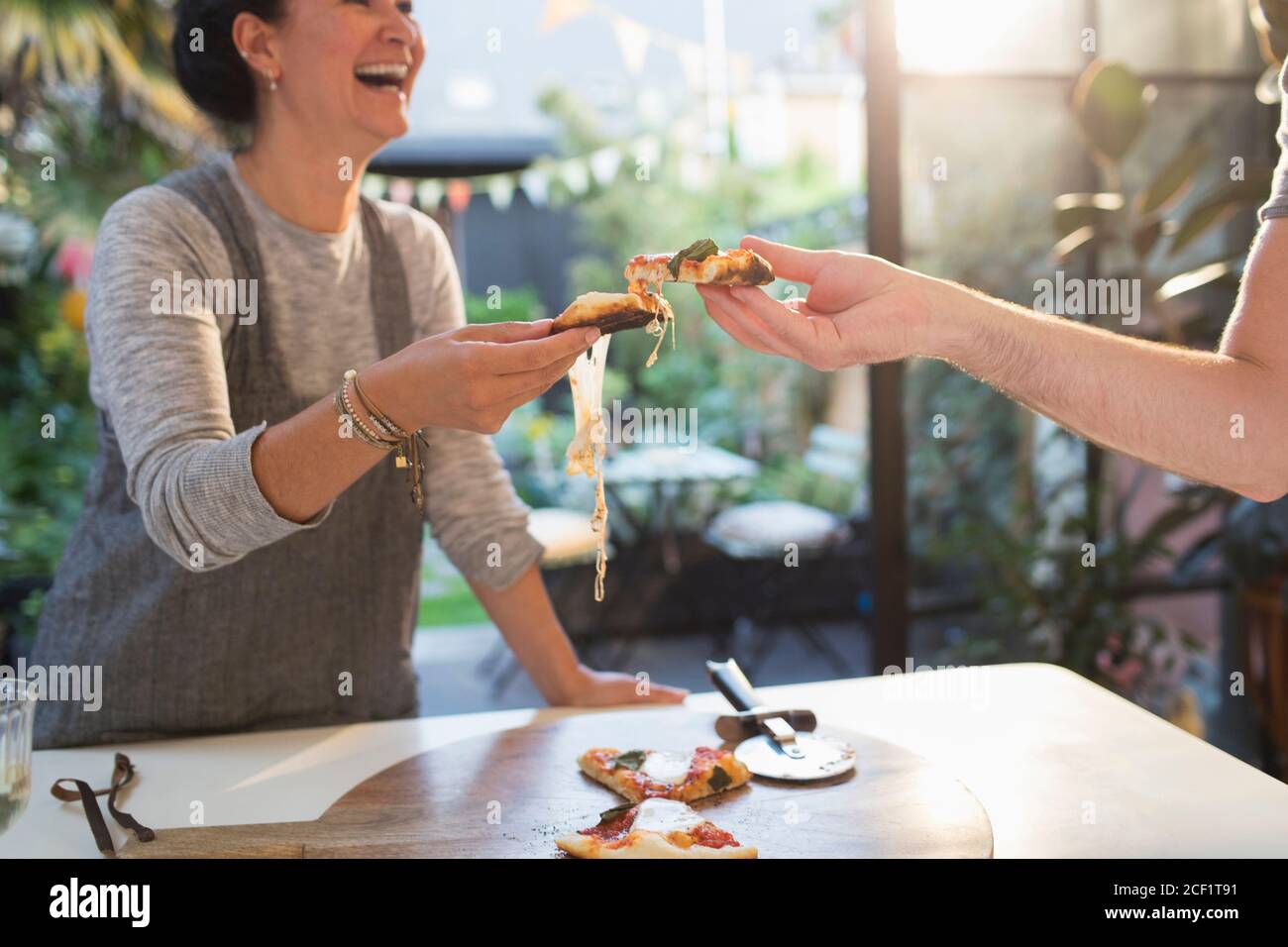 Buona coppia gustando la pizza fatta in casa in una cucina soleggiata Foto Stock