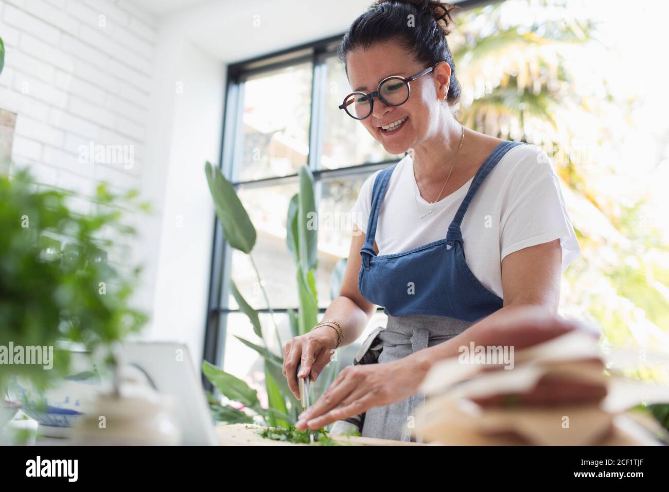 Donna sorridente che cucinava al tablet digitale in cucina Foto Stock