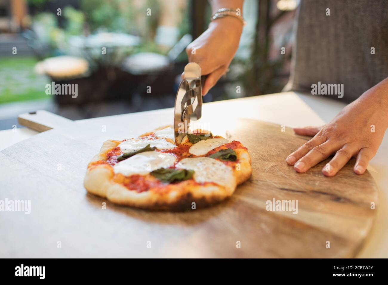 Donna tagliando pizza fresca fatta in casa con affettatrice Foto Stock