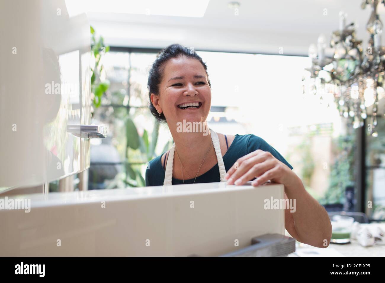 Donna felice che ride al frigorifero aperto Foto Stock