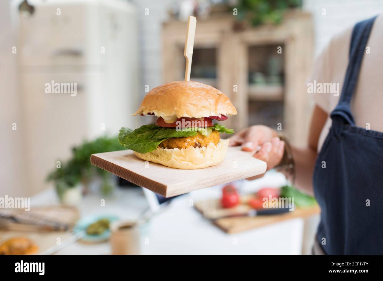Primo piano donna che tiene cheeseburger sul tagliere Foto Stock