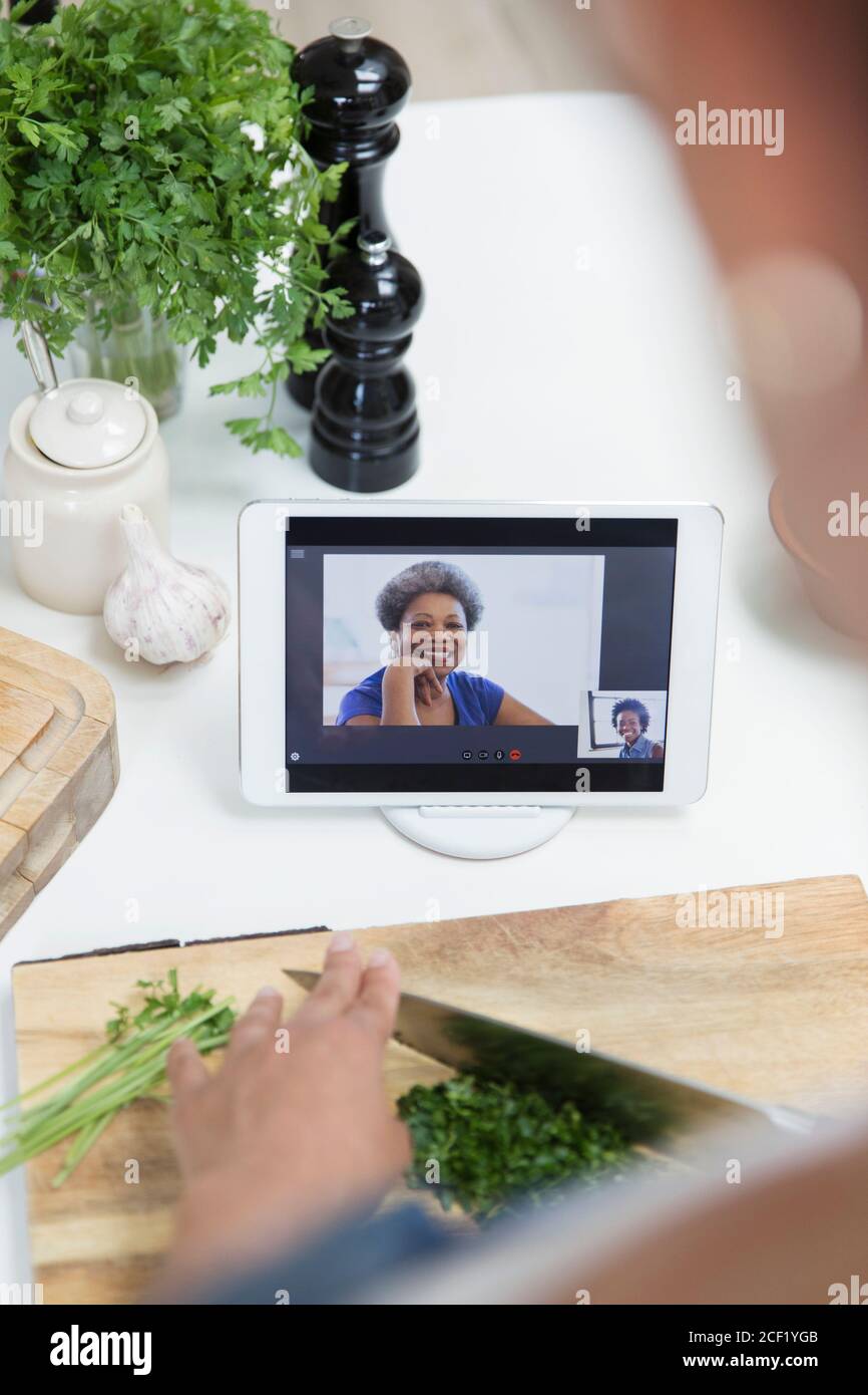 Donna che cucina e video chat con gli amici su tablet digitale schermo Foto Stock