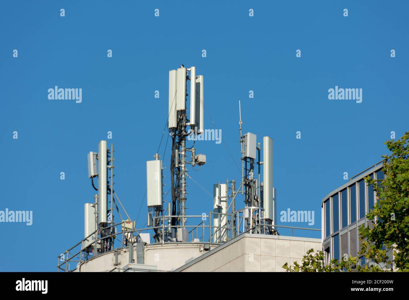 Antenne per telefoni cellulari 5G e 4G installate sul tetto di un edificio. Cielo blu Foto Stock