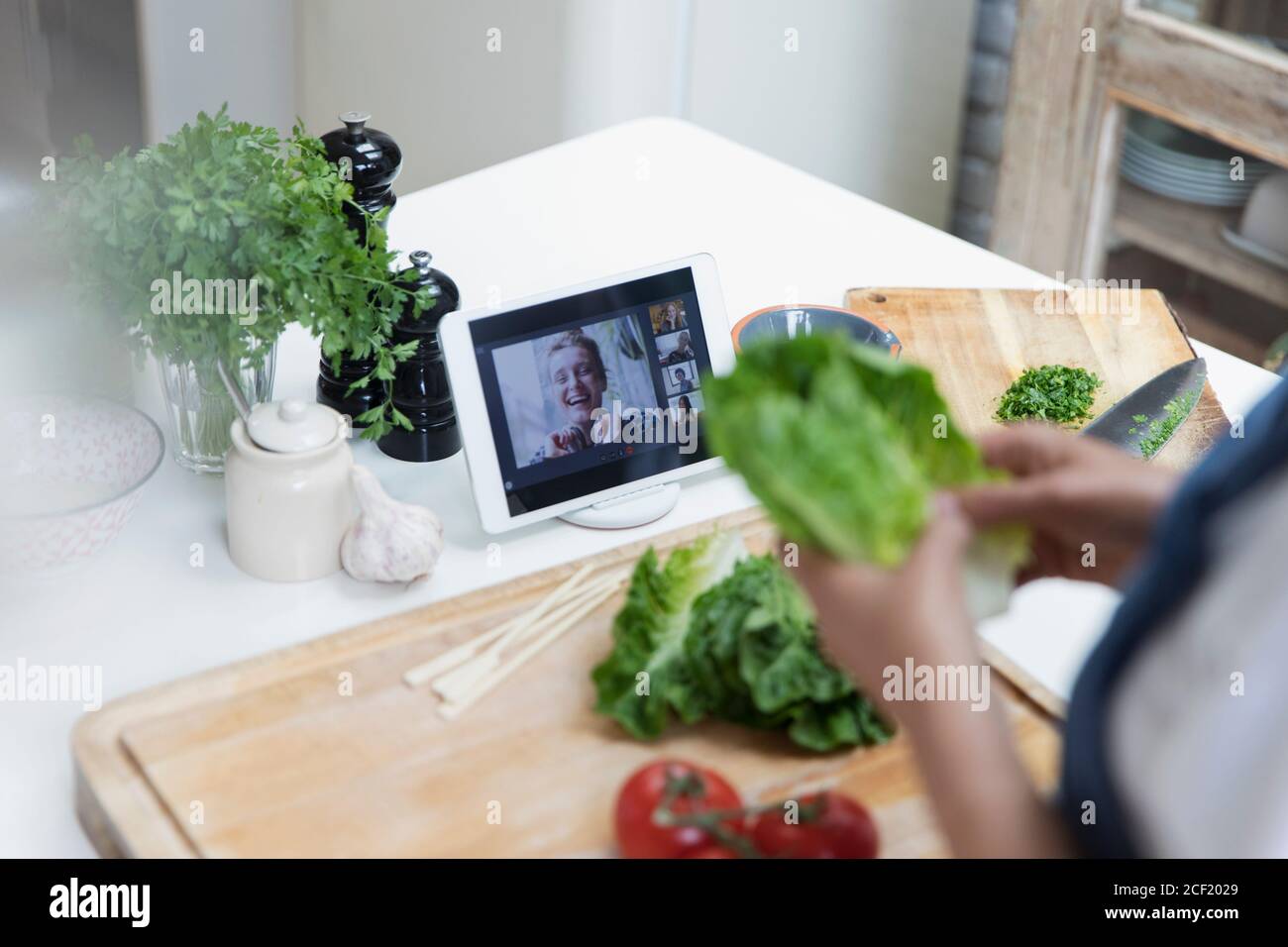 Donna che cucina e video chat con gli amici su tablet digitale schermo Foto Stock