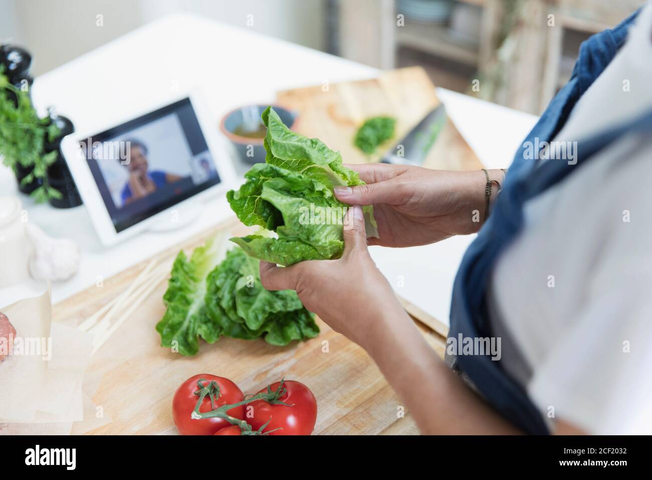 Donna che cucina e video chat con tablet digitale in cucina Foto Stock