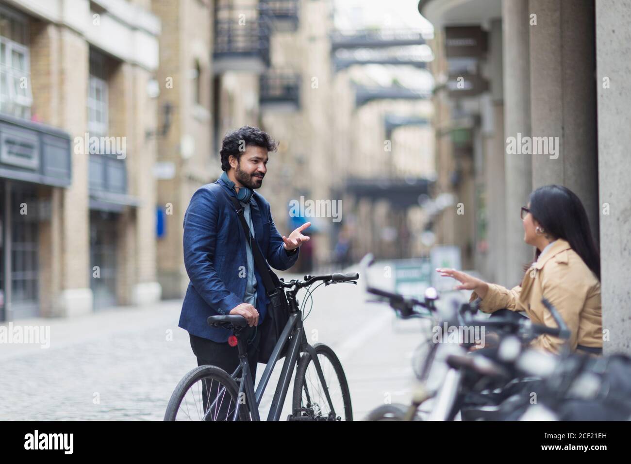 Uomini d'affari con biciclette che parlano sulla strada della città Foto Stock
