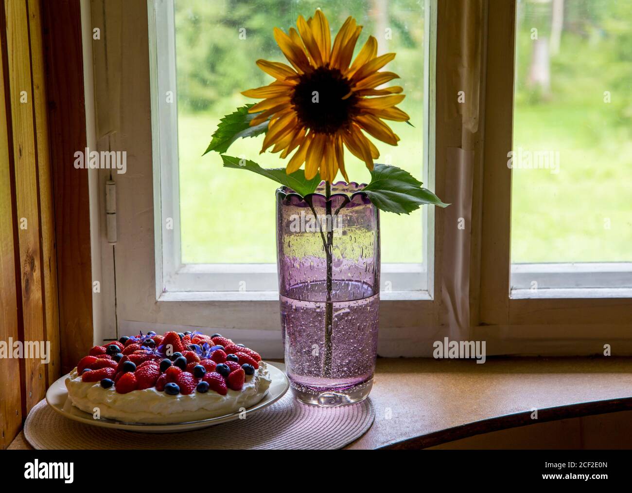 Tallinn, Harjumaa/ Estonia-29AUG2020: Vaso da collezione di Tarbeklaas chiamato Sammal con girasole e torta estiva sulla soglia della finestra. Foto Stock