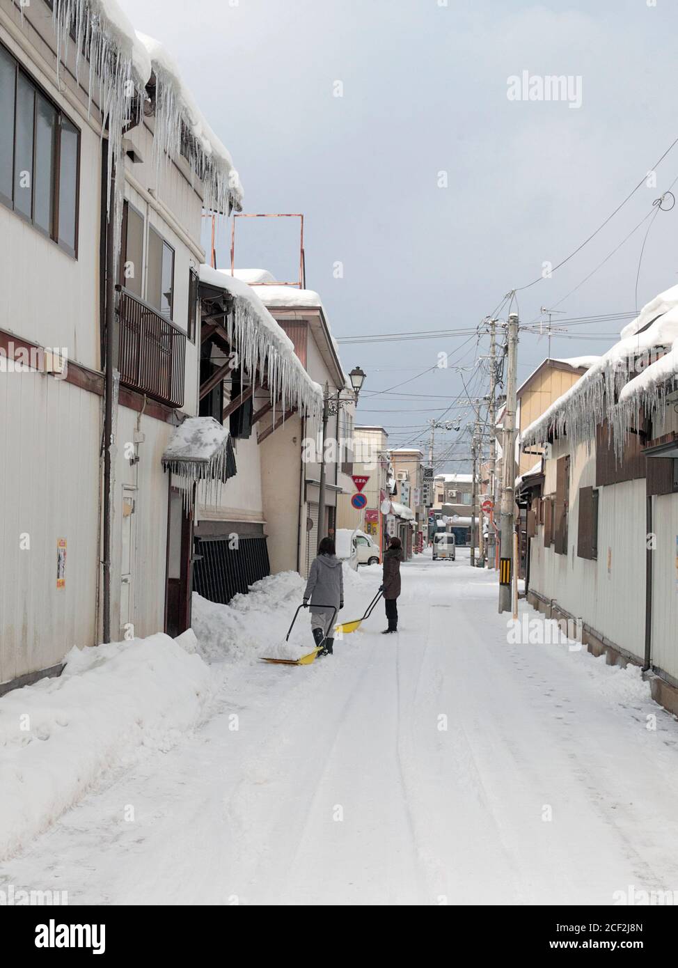 Scena di strada, due donne che liberano neve e icicles, Kakunodate, nord Honshu, Giappone 16 Feb 2019 Foto Stock