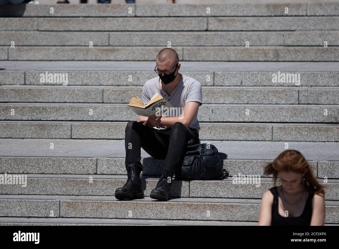 Un uomo legge il libro "perché non sto più parlando con i bianchi della corsa" sui gradini di Trafalgar Square, Londra Foto Stock