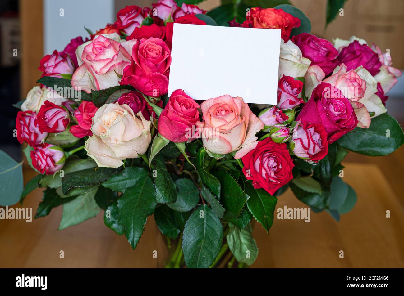 Bouquet di rose rosse, rosa e gialle con cartoncino vuoto. Modello per il compleanno, il matrimonio, il giorno della madre, il biglietto di San Valentino. Foto Stock