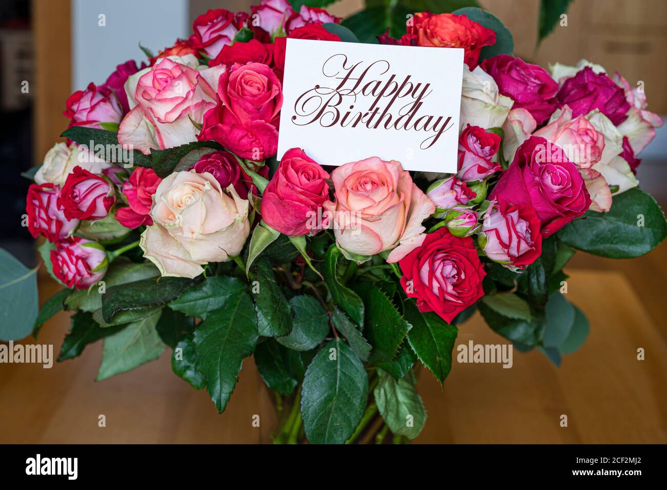 Bouquet di rose rosse, rosa e gialle con buono di buon compleanno. Modello per il biglietto di compleanno. Foto Stock
