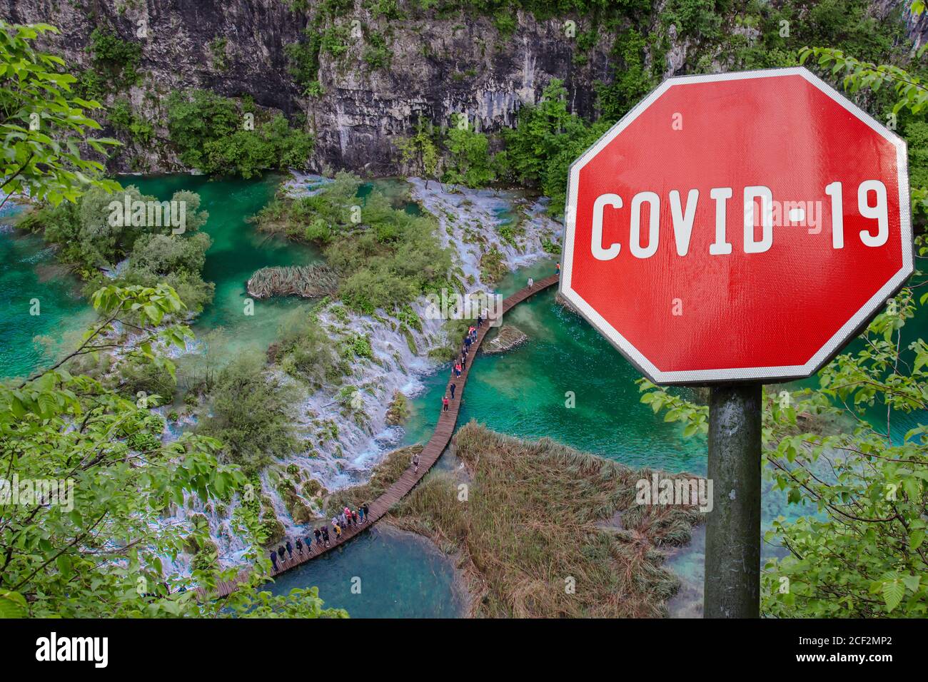 COVID-19 segno contro la vista dall'alto della cascata con acqua turchese nel Parco Nazionale dei Laghi di Plitvice, Croazia. Malattia del coronavirus. COVID-2 Foto Stock