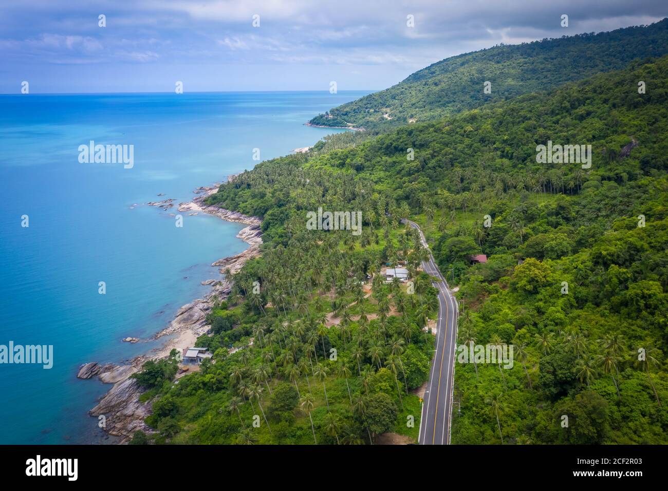 Vista aerea della strada tra palme da cocco e il grande oceano di giorno a Nakhon si Thammarat, Thailandia Foto Stock