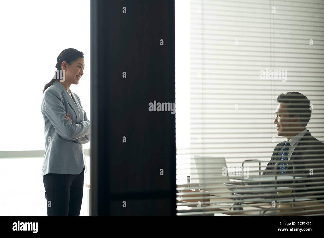 giovane uomo d'affari asiatico e donna d'affari che chiacchiera parlando di affari dentro ufficio moderno Foto Stock