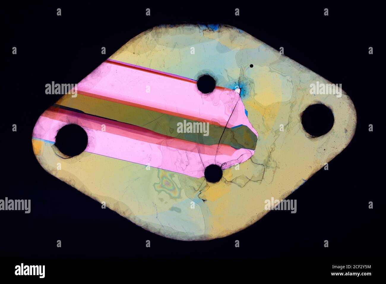 Rondella mica, utilizzata per isolare un semiconduttore di potenza dal suo dissipatore di calore, fotografata tra polarizzatori incrociati. Foto Stock