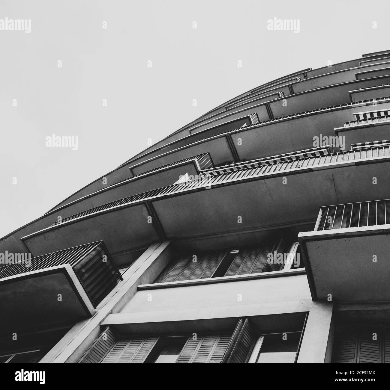 Dettaglio architettonico. Angolo di vista con disegno a labirinto grafico dell'edificio con balconi e ombrellone a strisce. Foto in bianco e nero. Foto Stock