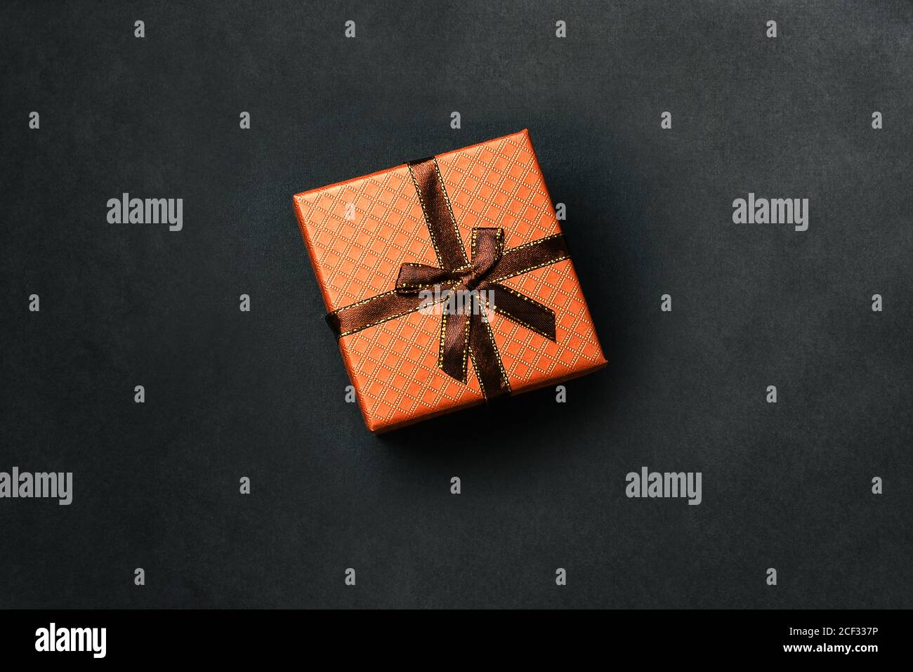 Confezione regalo con nastro su sfondo scuro. Confezione marrone per feste di compleanno, Natale, matrimoni e altri eventi festosi. Vista dall'alto su una superficie piatta Foto Stock