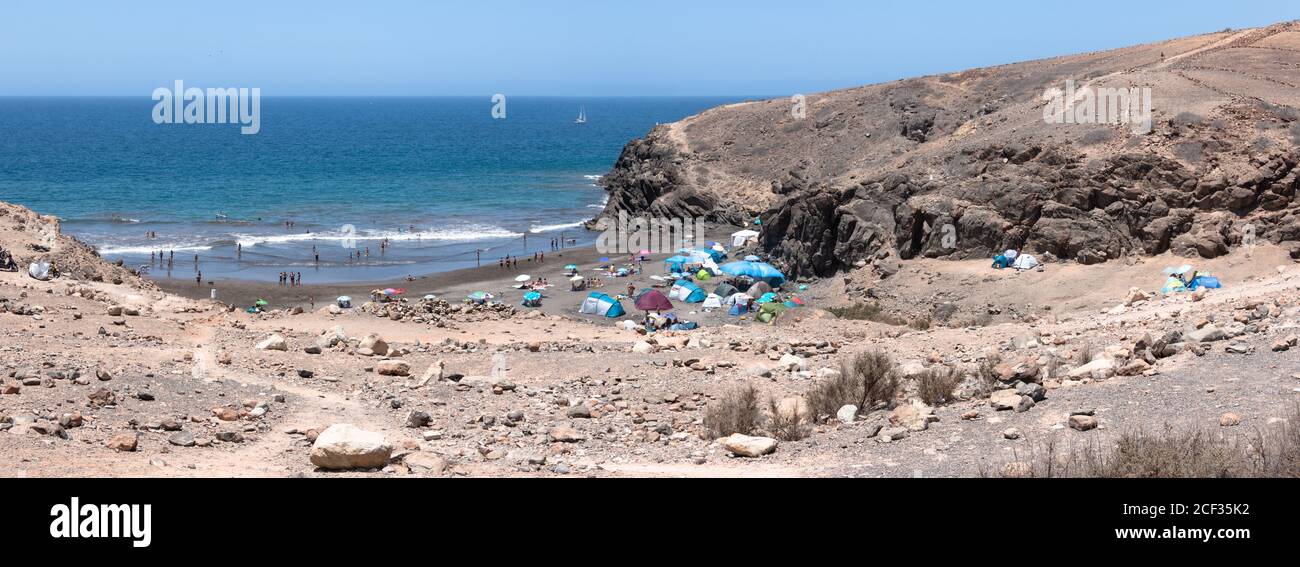 Scenario di una spiaggia rocciosa piena di persone nell'isola di Gran Canaria. Concetto di viaggio Foto Stock