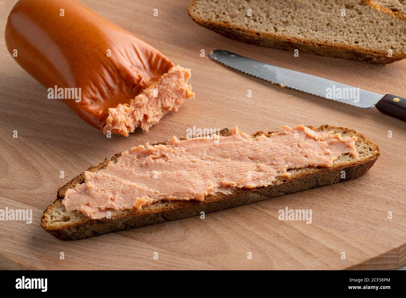 Teewurst tedesco tradizionale a una fetta di pane sourdough vicino su Foto Stock
