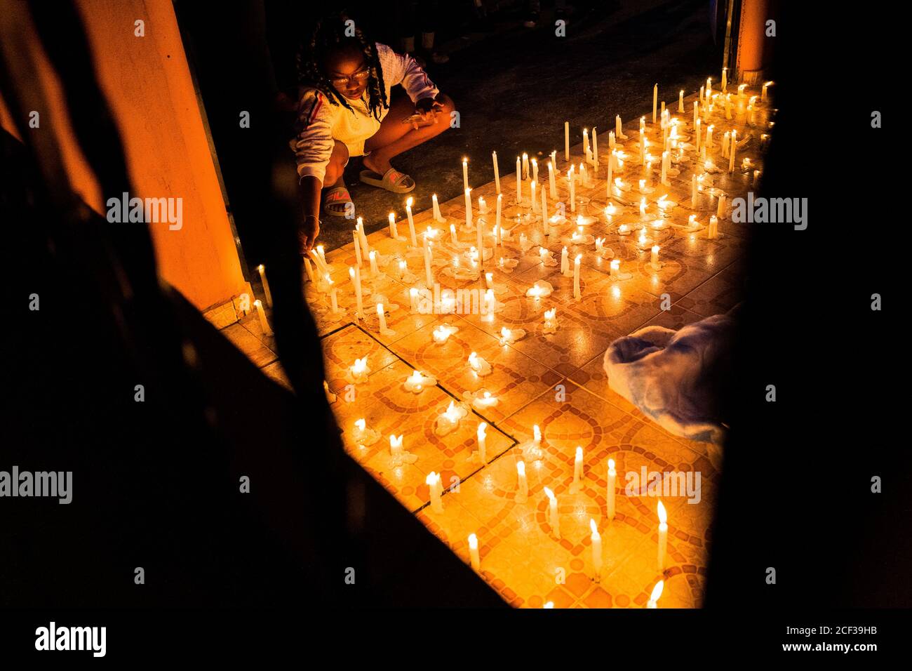 Un seguace cattolico afro-colombiano accende una candela mentre partecipa a una processione religiosa durante il festival di San Pacho a Quibdó, Colombia. Foto Stock