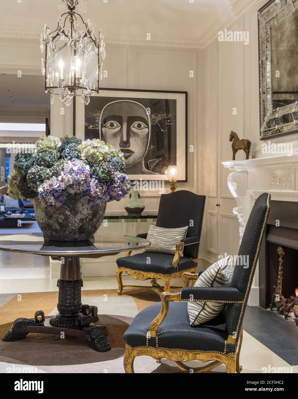 Fiore di disposizione sotto il lampadario con poltrone Foto Stock