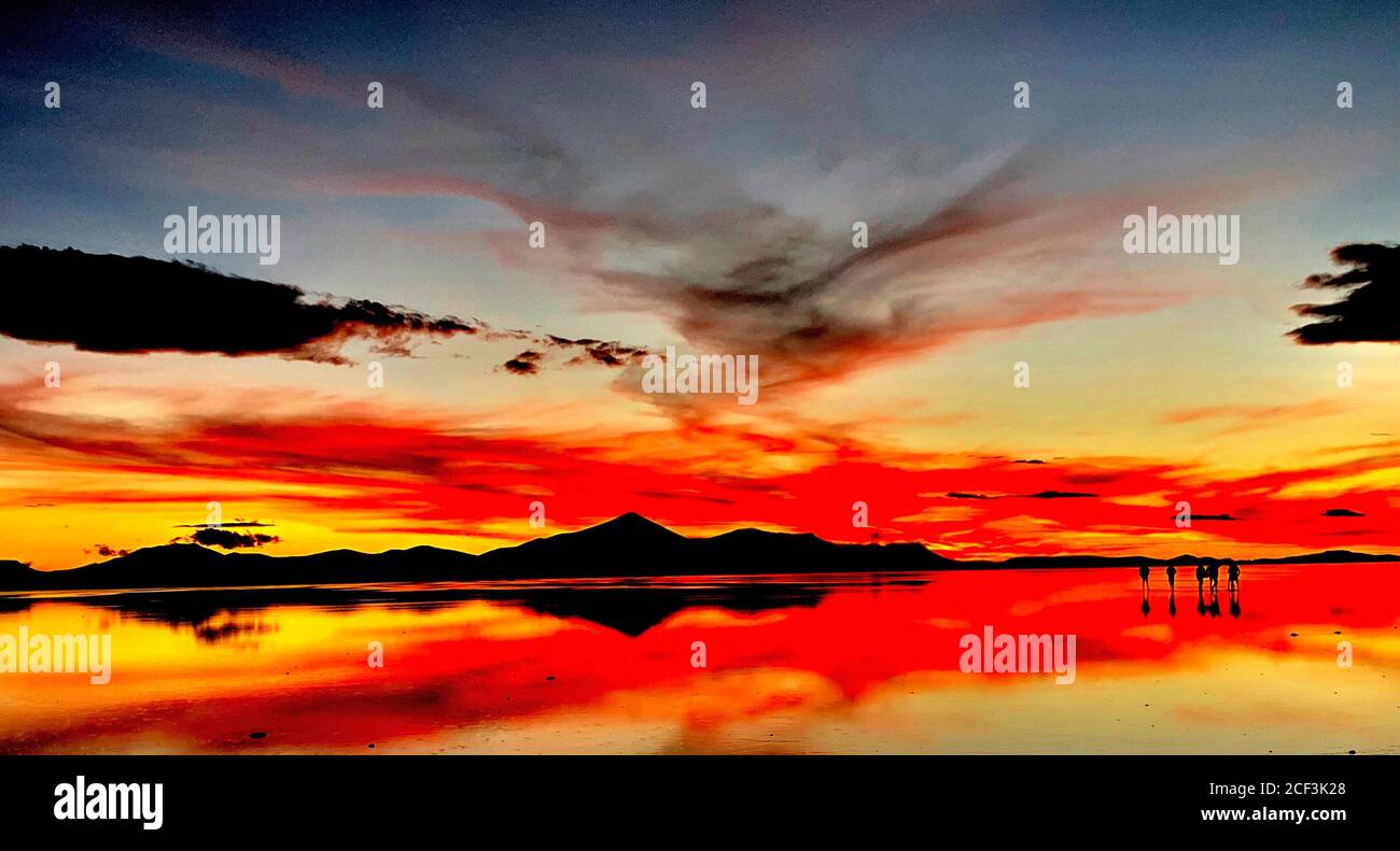 Spettacolare tramonto rosso su Salar de Uyuni, deserto Atacama. Altopiano di Altiplano, Bolivia, Sud America. Il cielo magico riflesso nell'acqua del lago. Foto Stock