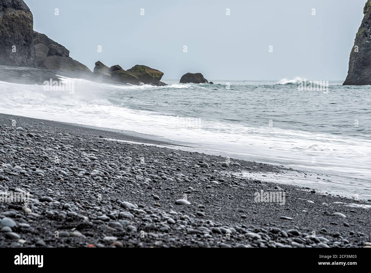 Islanda Reynisfjara rocce di sabbia nera sulla roccia vulcanica Vik formazioni con nessuno e onde che si infrangono sulla costa costiera Foto Stock