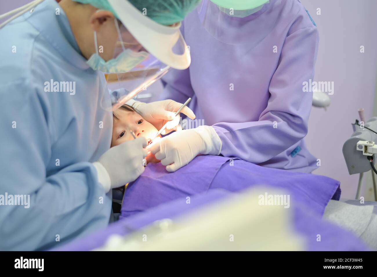 dentista che esamina e cura i denti del bambino della ragazza in clinica dentale servizio Foto Stock