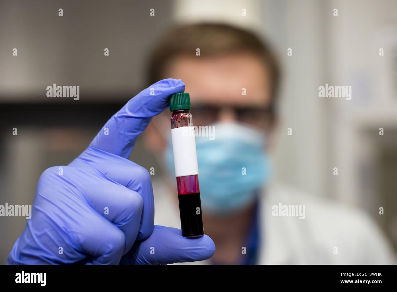 Scienziato in un laboratorio che tiene una fiala piccola per un esame del sangue. Nel mondo Covid-19 pandemia Foto Stock