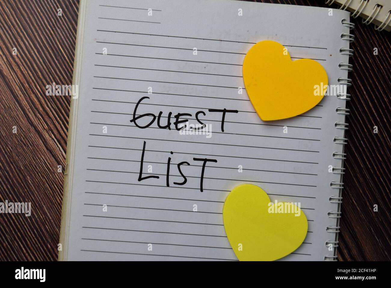 Guest List scrivere su un libro con parole chiave isolato tavola di legno. Foto Stock