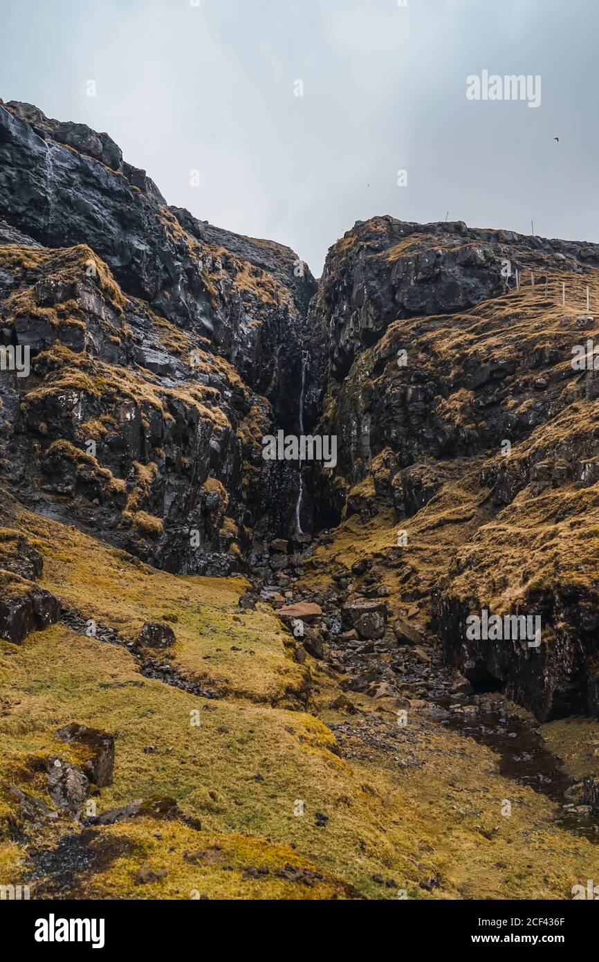 Cascata d'acqua che cade dalle montagne nelle isole Faroe Foto Stock