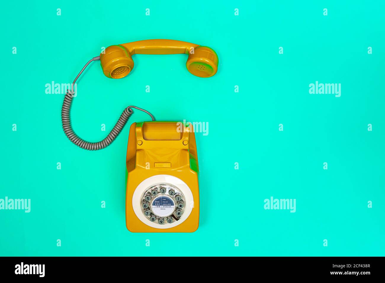 Ricevitore giallo di un telefono su sfondo verde. Moderno stile retrò. Nuova vecchia tecnologia. Foto Stock