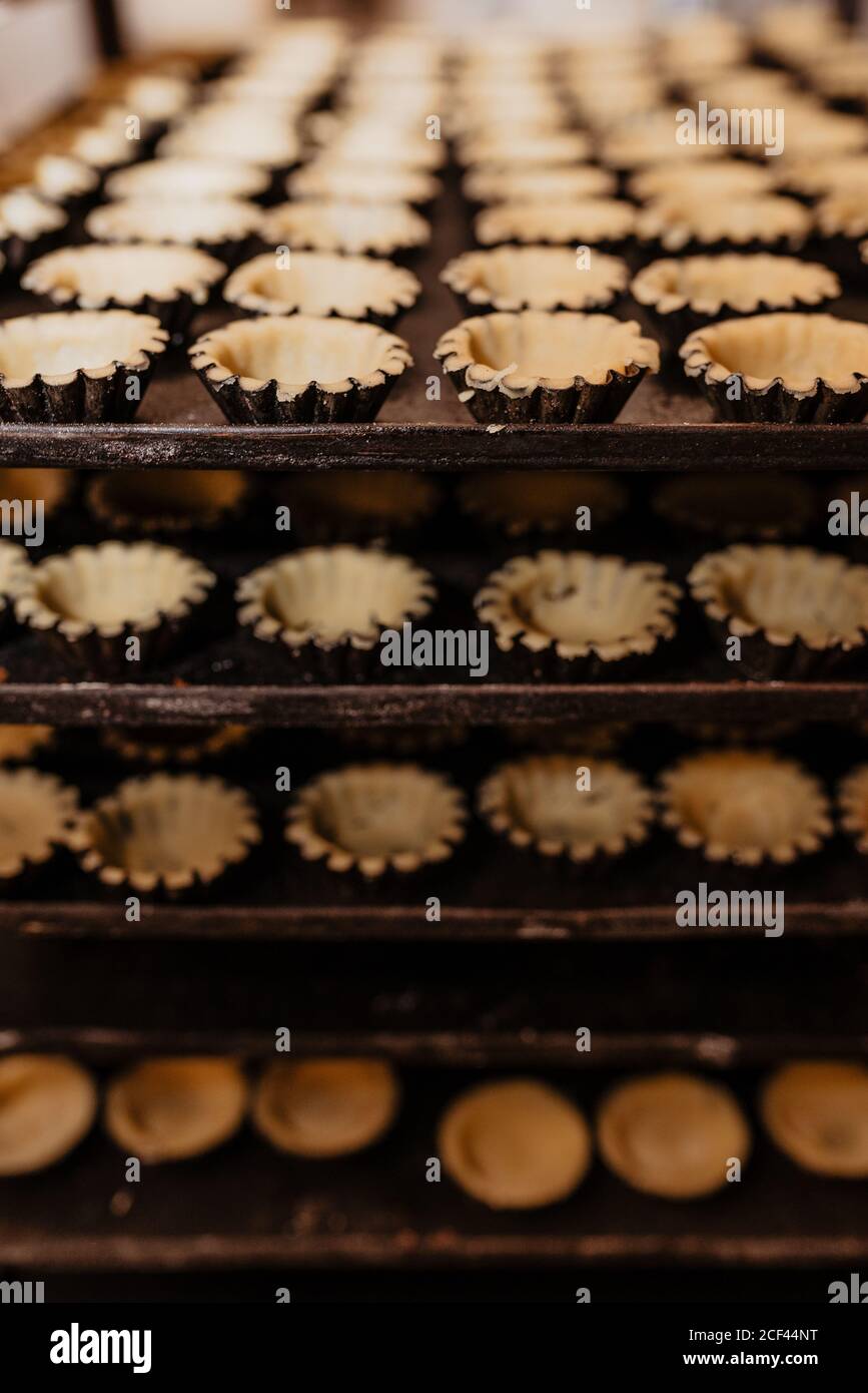 Set di custodie per pasticceria grezza vuote poste su vassoi di metallo in panetteria Foto Stock