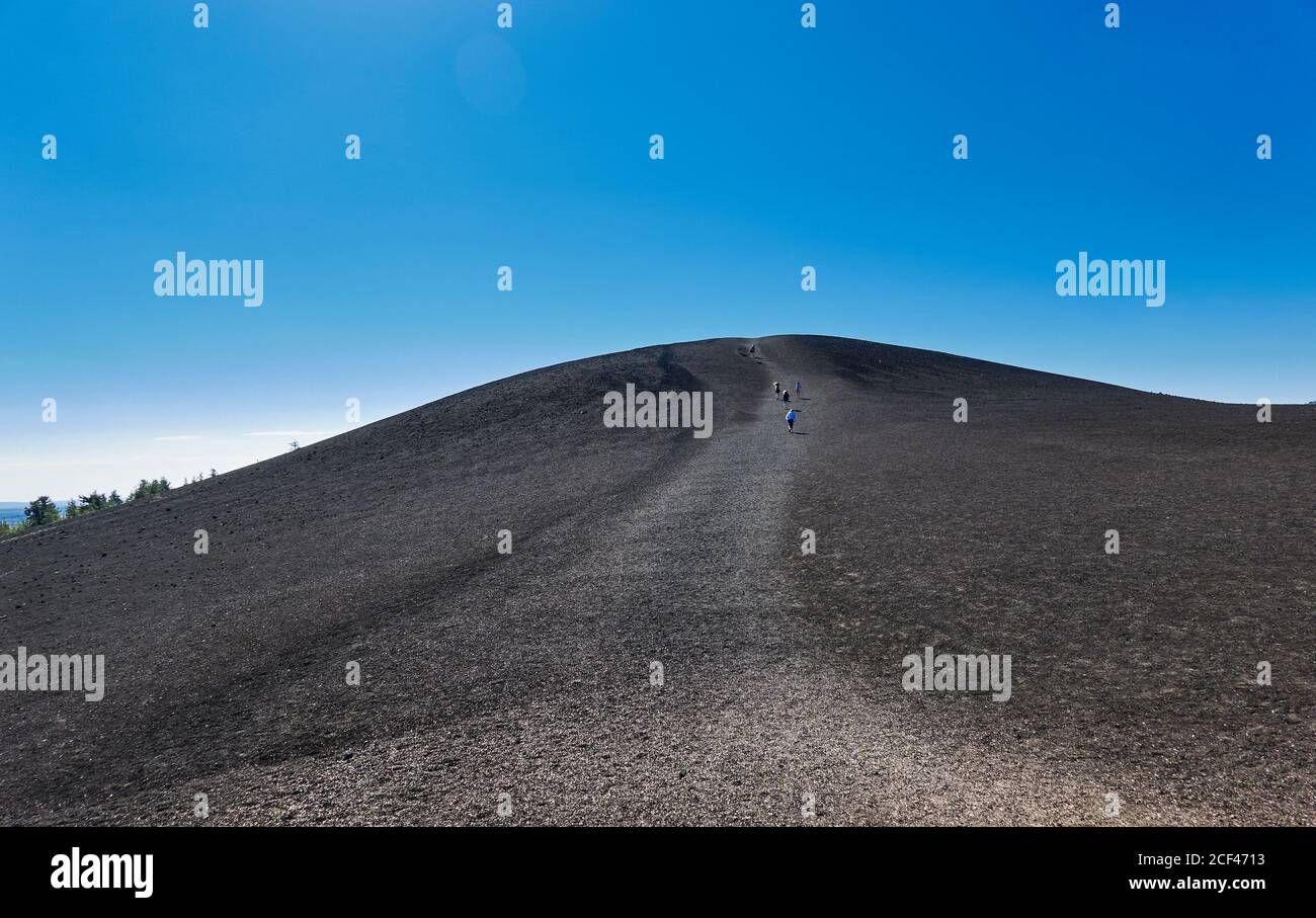 Persone che camminano fino alla cima del cono Inferno al Craters of the Moon National Park. Foto Stock