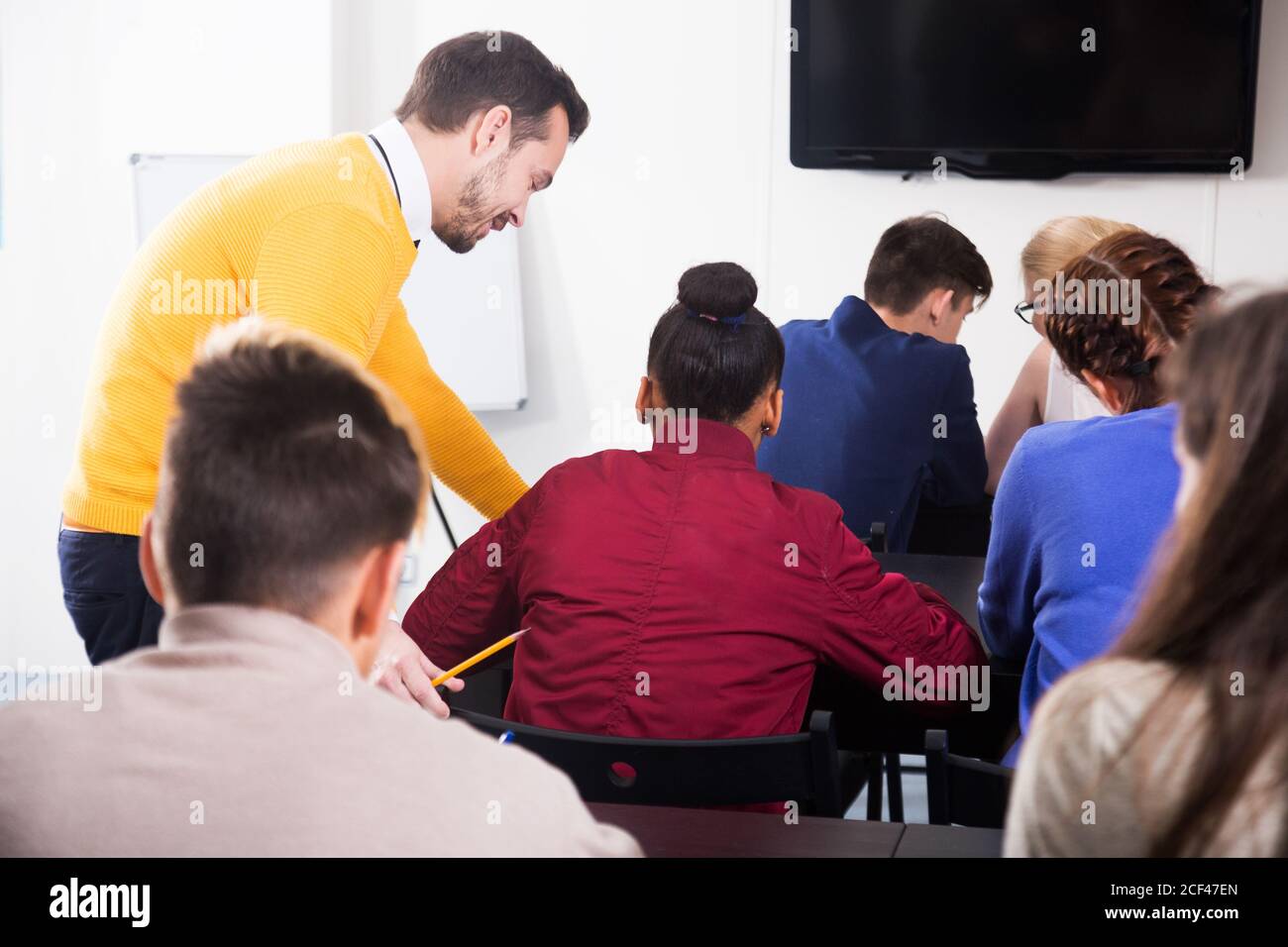 Insegnante adulto che fornisce una spiegazione allo studente durante il lavoro di revisione in classe Foto Stock