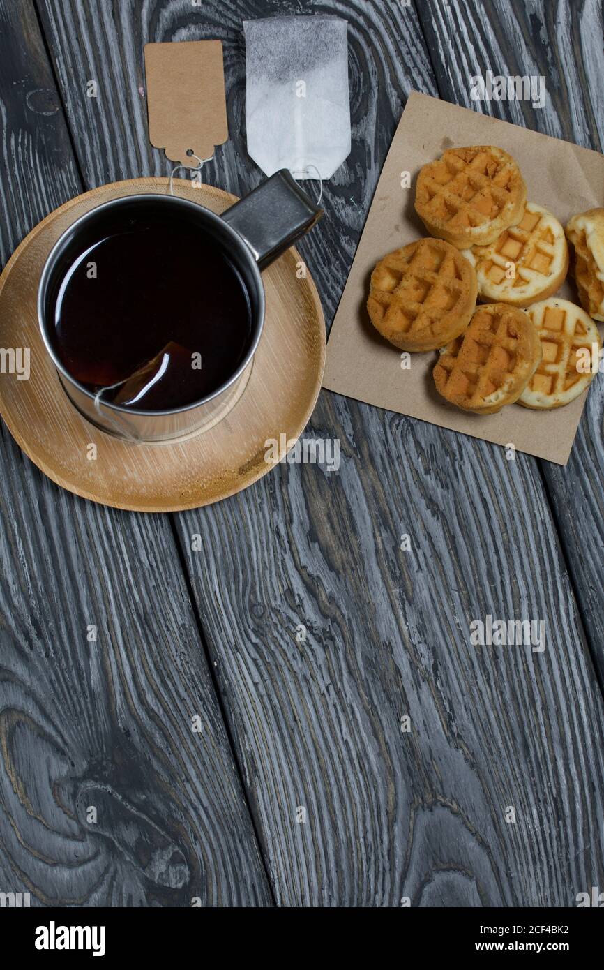 Tazza di tè e waffle. Nelle vicinanze si trova una borsa per il tè. Su tavole verniciate. Autunno ancora vita. Ripresa dall'alto. Foto Stock