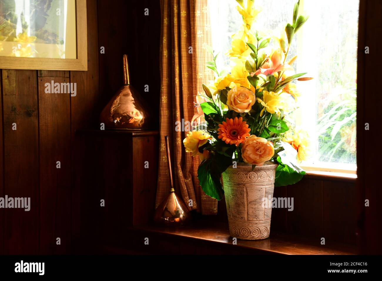 Disposizione colorata dei fiori con imbuti di rame su una finestra soleggiata Sill in una casa pubblica in Devon.UK Foto Stock