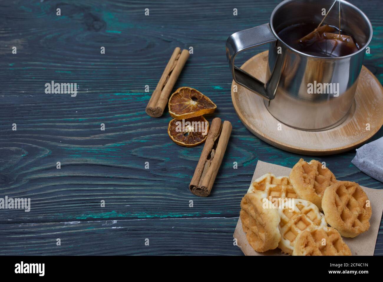 Tazza di tè e waffle. Nelle vicinanze si trova una bustina di tè e spezie. Su tavole verniciate. Autunno ancora vita. Foto Stock