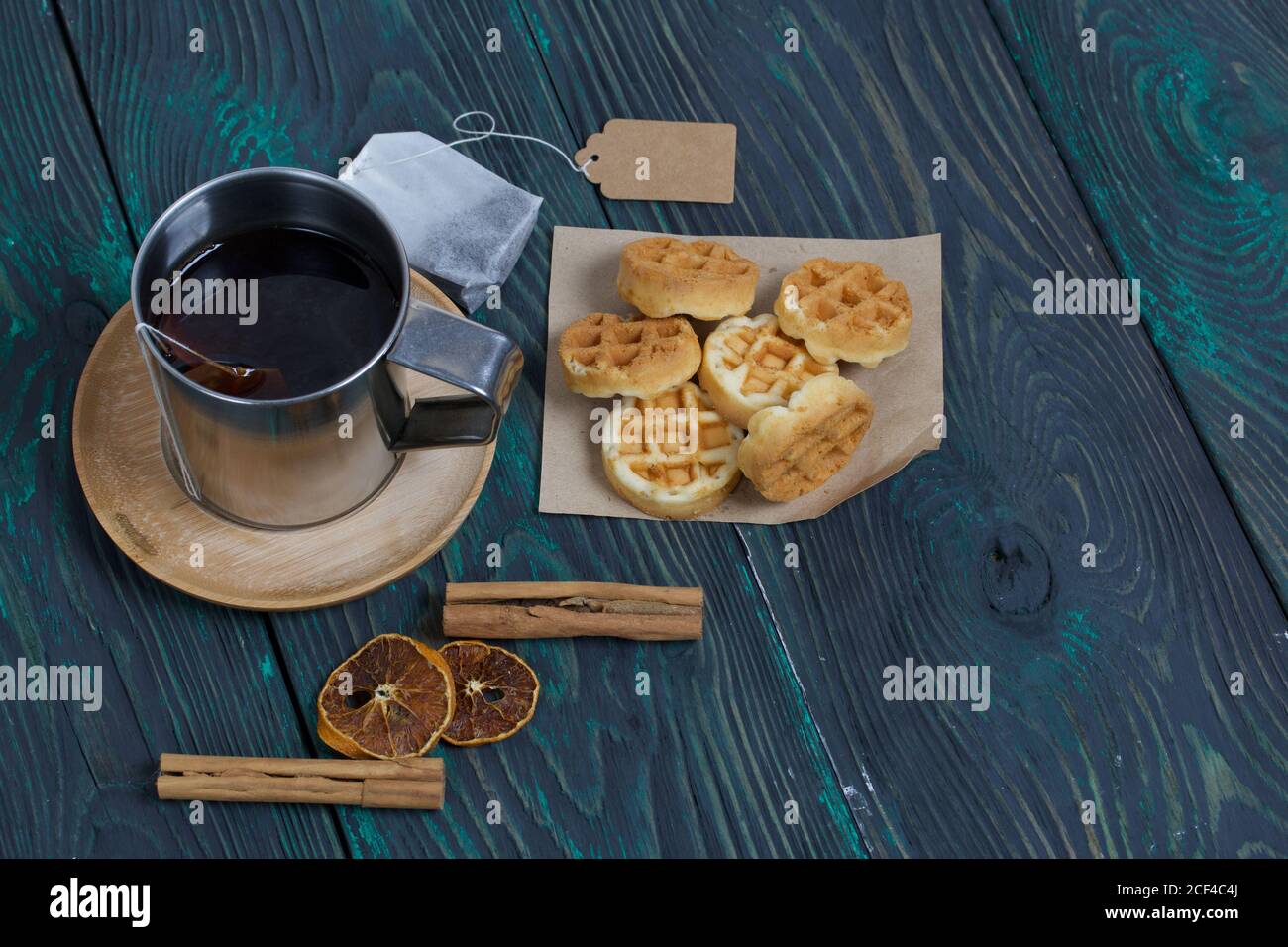 Tazza di tè e waffle. Nelle vicinanze si trova una bustina di tè e spezie. Su tavole verniciate. Autunno ancora vita. Foto Stock