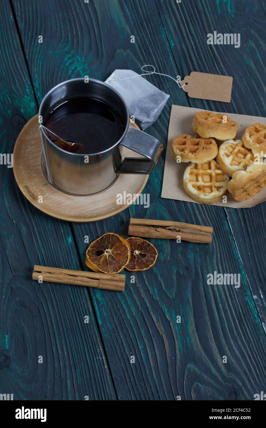 Tazza di tè e waffle. Nelle vicinanze si trova una bustina di tè e spezie. Su tavole verniciate. Autunno ancora vita. Foto Stock