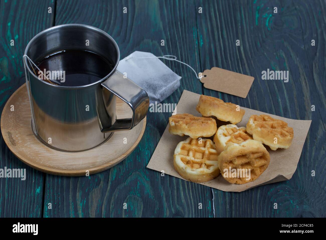 Tazza di tè e waffle. Nelle vicinanze si trova una borsa per il tè. Su tavole verniciate. Autunno ancora vita. Foto Stock