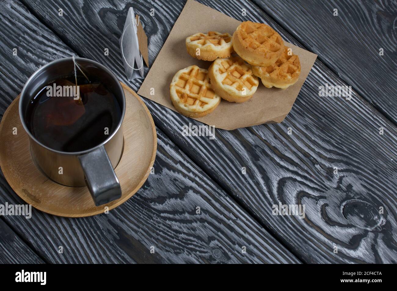 Tazza di tè e waffle. Nelle vicinanze si trova una borsa per il tè. Su tavole verniciate. Autunno ancora vita. Foto Stock