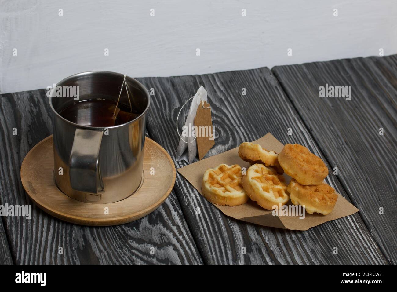 Tazza di tè e waffle. Nelle vicinanze si trova una borsa per il tè. Su tavole verniciate. Autunno ancora vita. Foto Stock