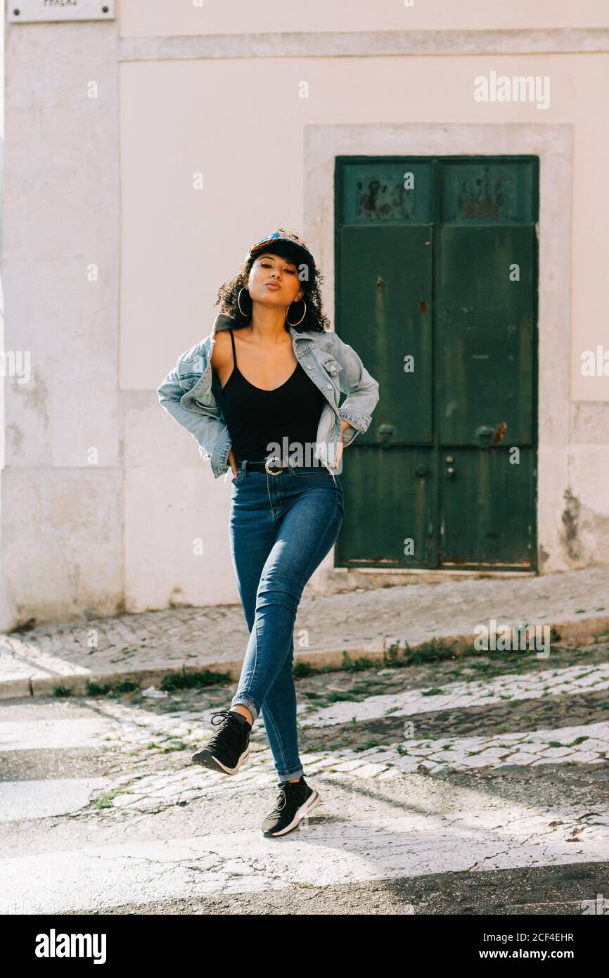 Giovane donna afro-americana allegra in jeans e t-shirt nera in strada città di giorno Foto Stock