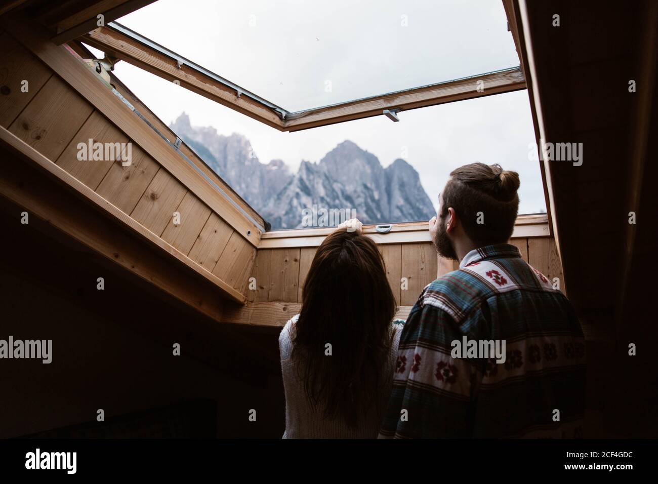 Da sotto la vista posteriore dei viaggiatori maschili e femminili senza volto In abbigliamento informale ammirando il paesaggio delle Dolomiti in Italia dal lucernario Foto Stock